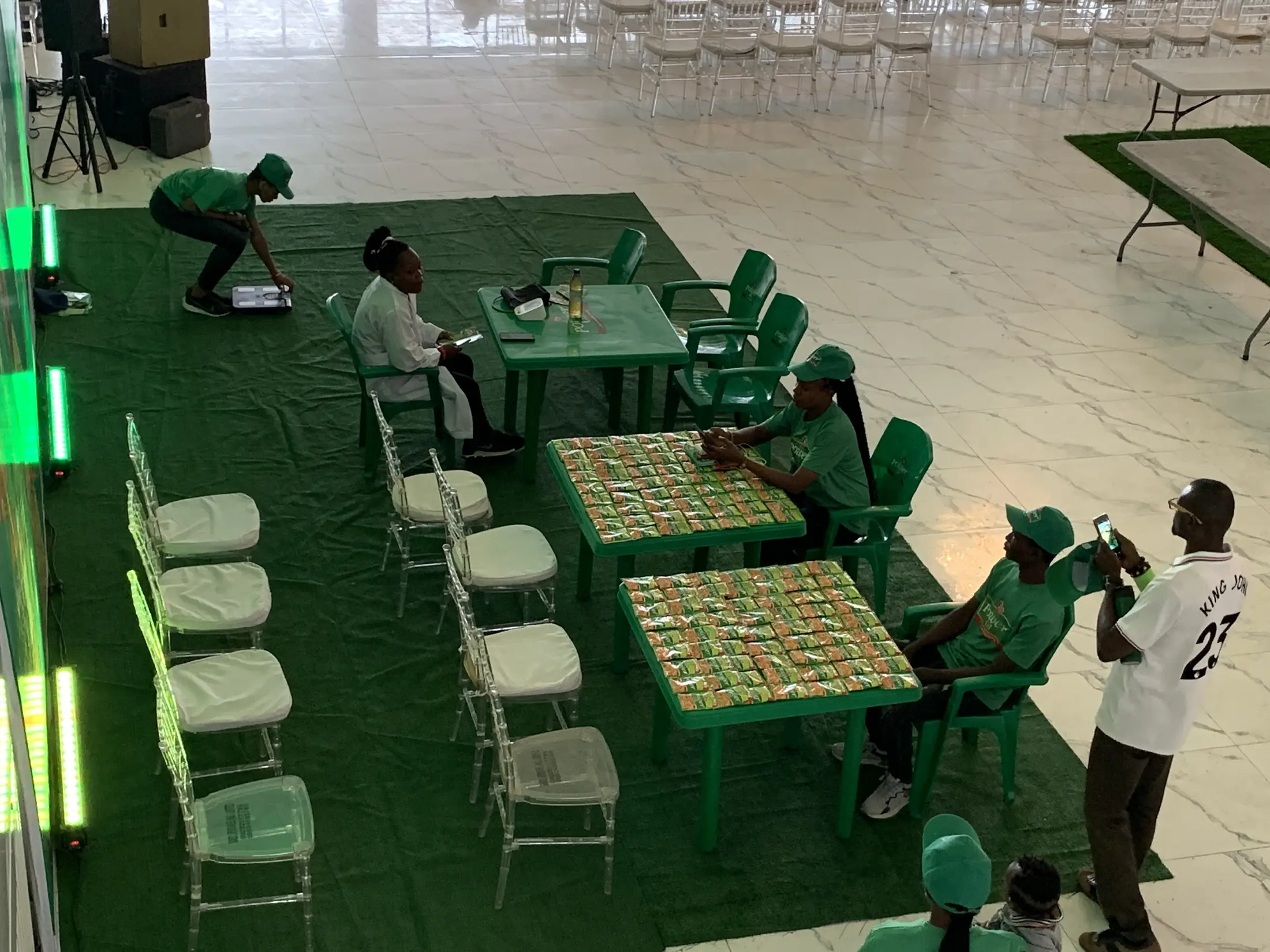 Workshop tables set on green matting in the daylit hall, a team preparing