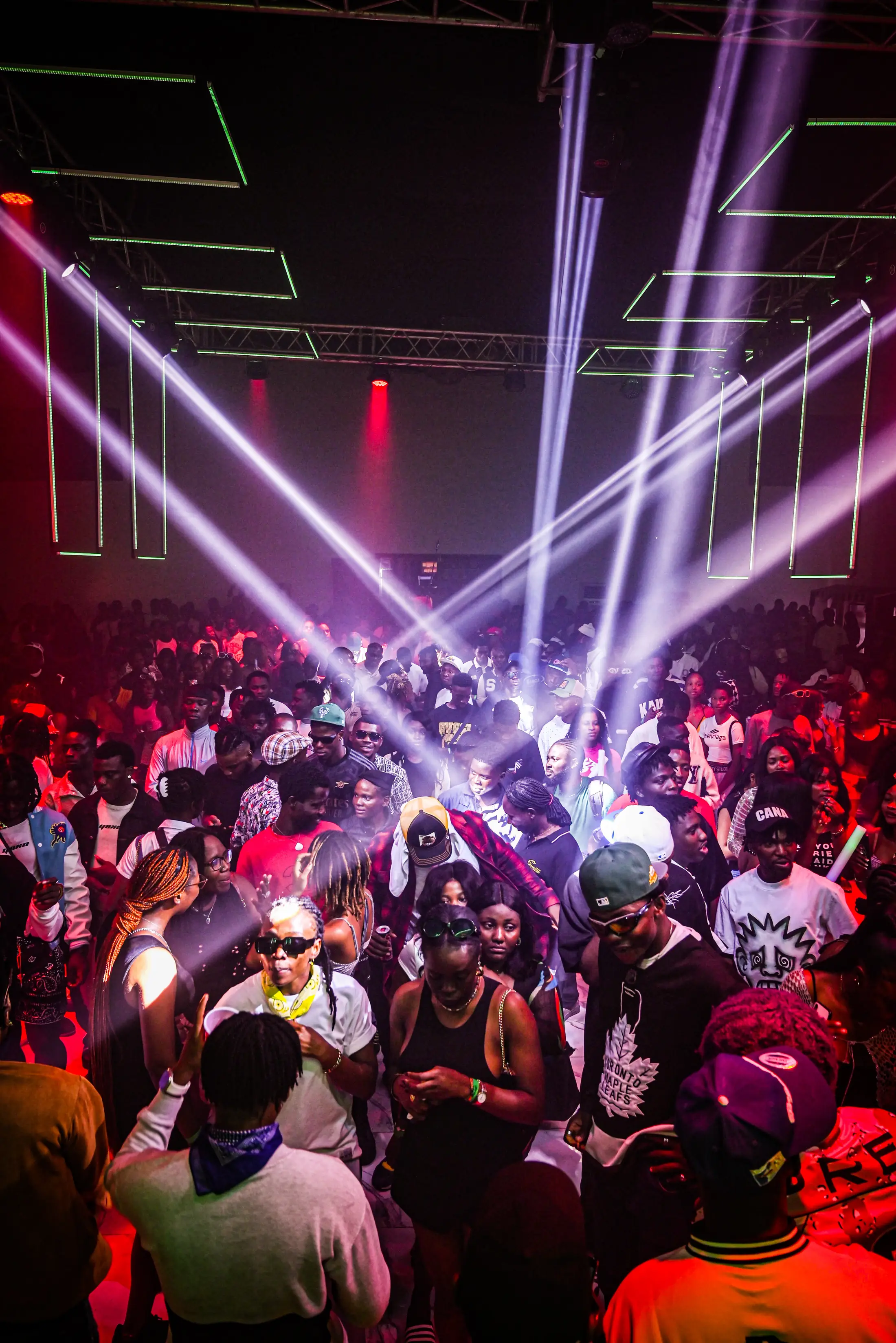 A packed dance floor under crossing stage lights at night