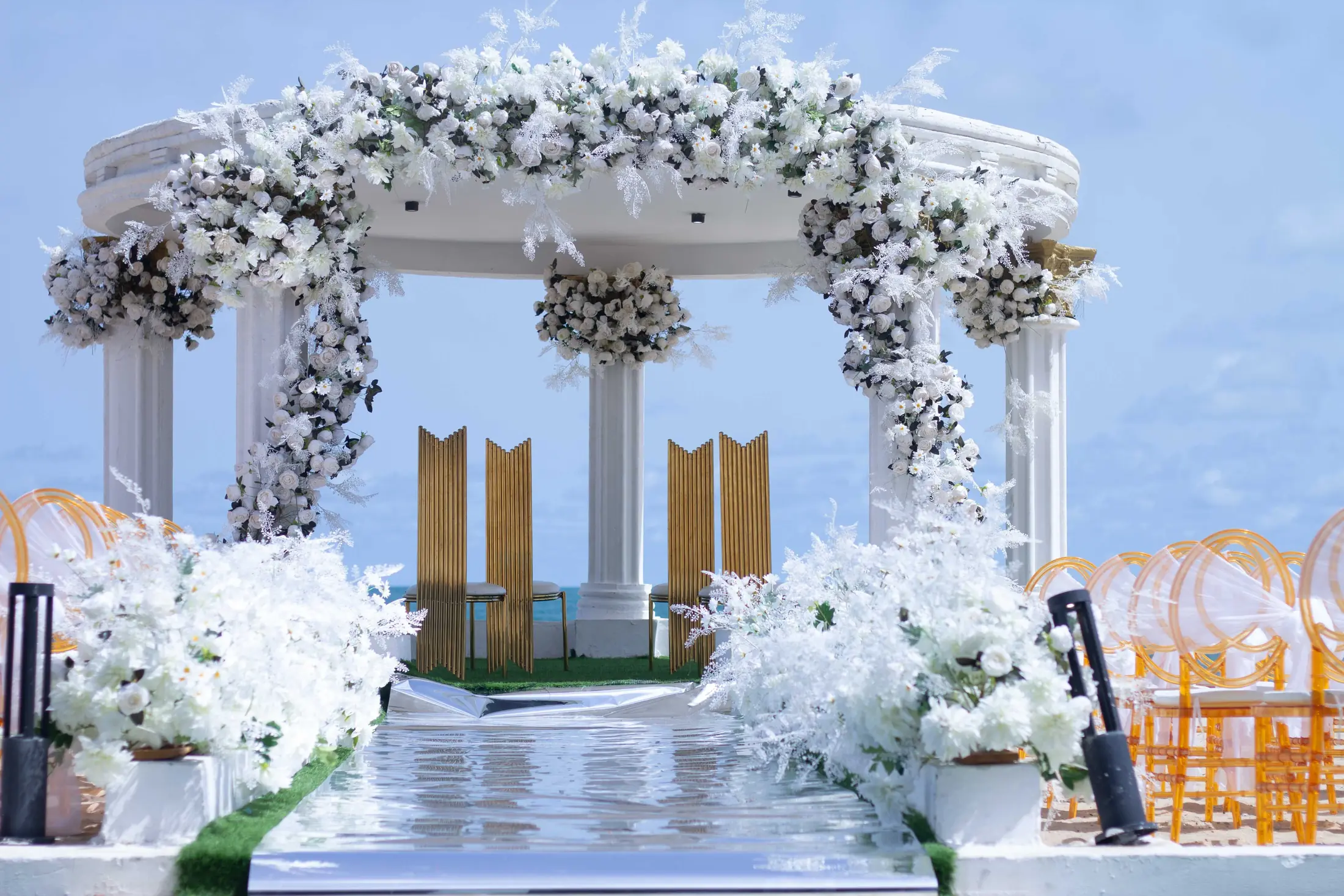The gazebo at the end of a white aisle lined with flowers