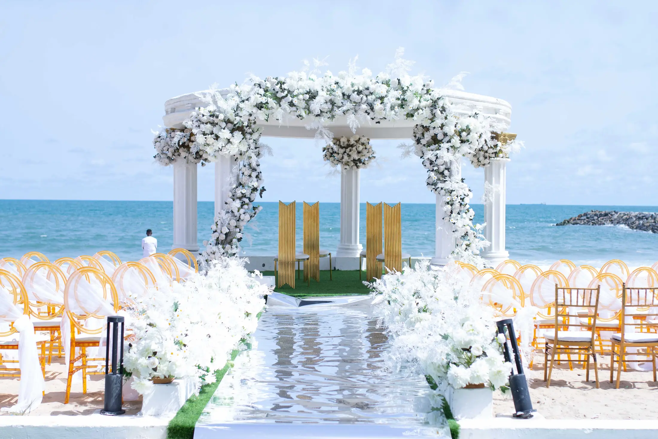 The flower-dressed gazebo on the sand at the end of the aisle