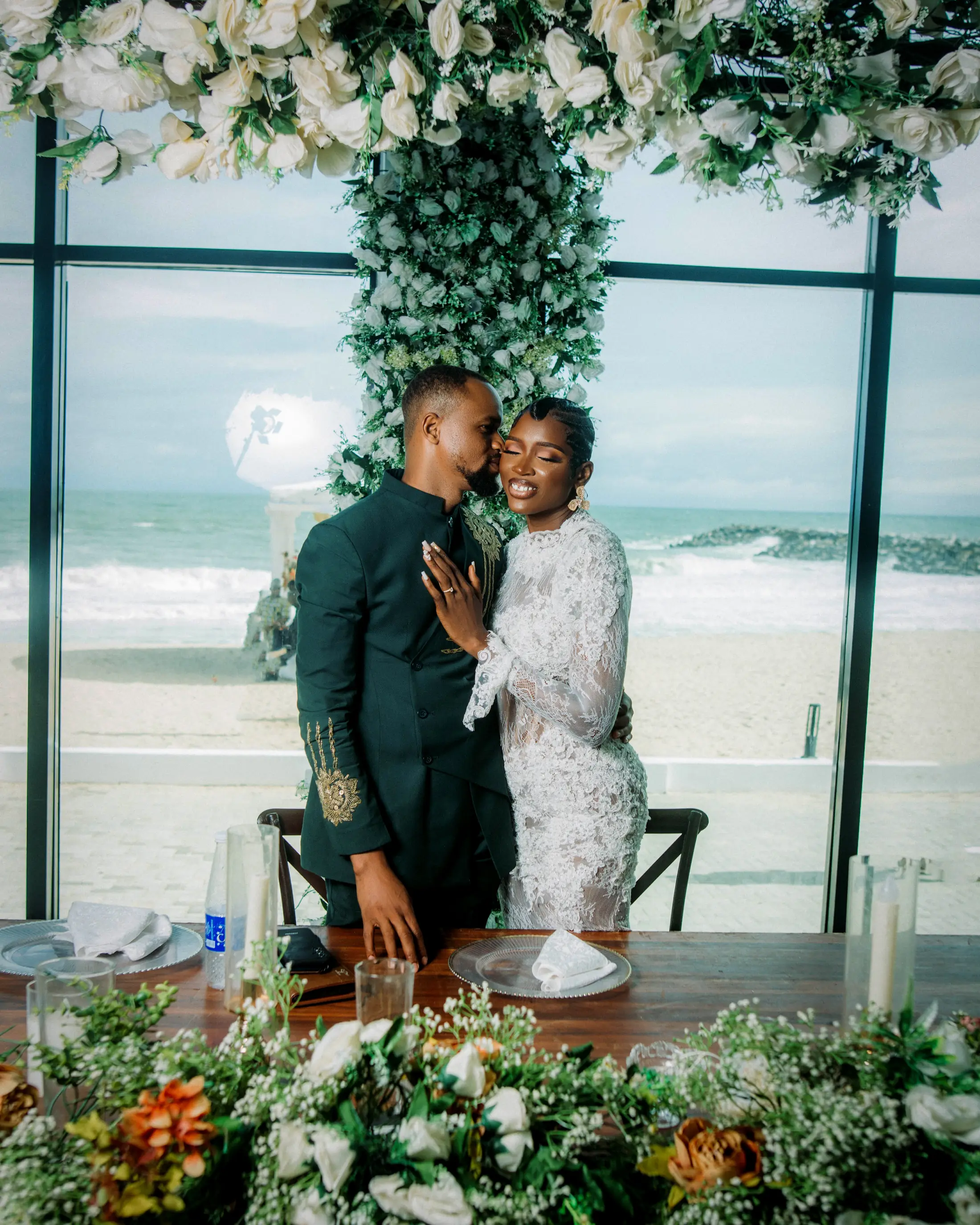 A bride and groom close together at their table by the glass