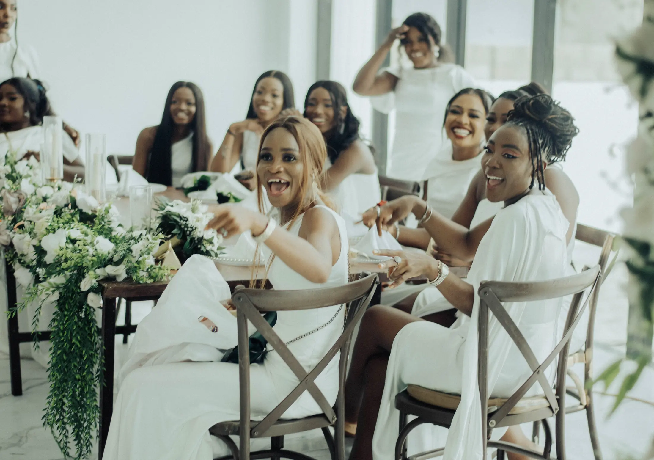 Bridesmaids in white laughing together at their table