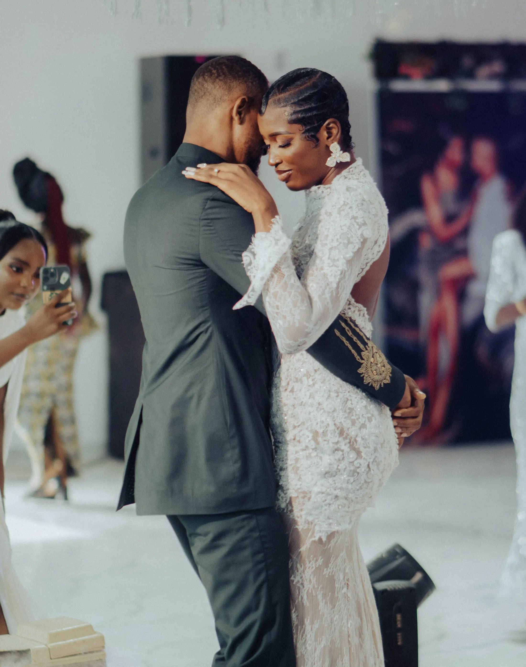 A couple in their first dance, the bride's lace dress catching the light