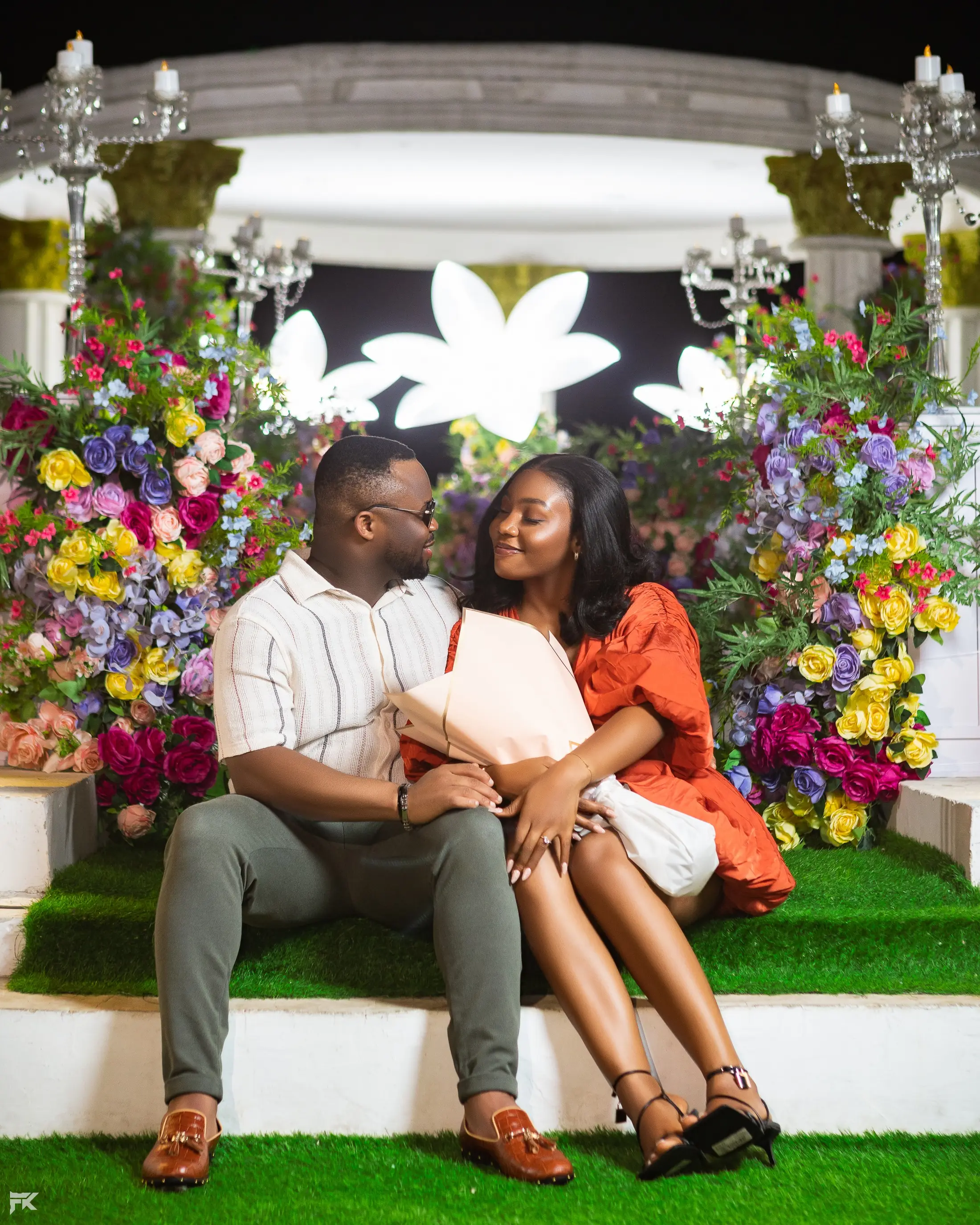 A couple sitting together inside a flower-filled gazebo