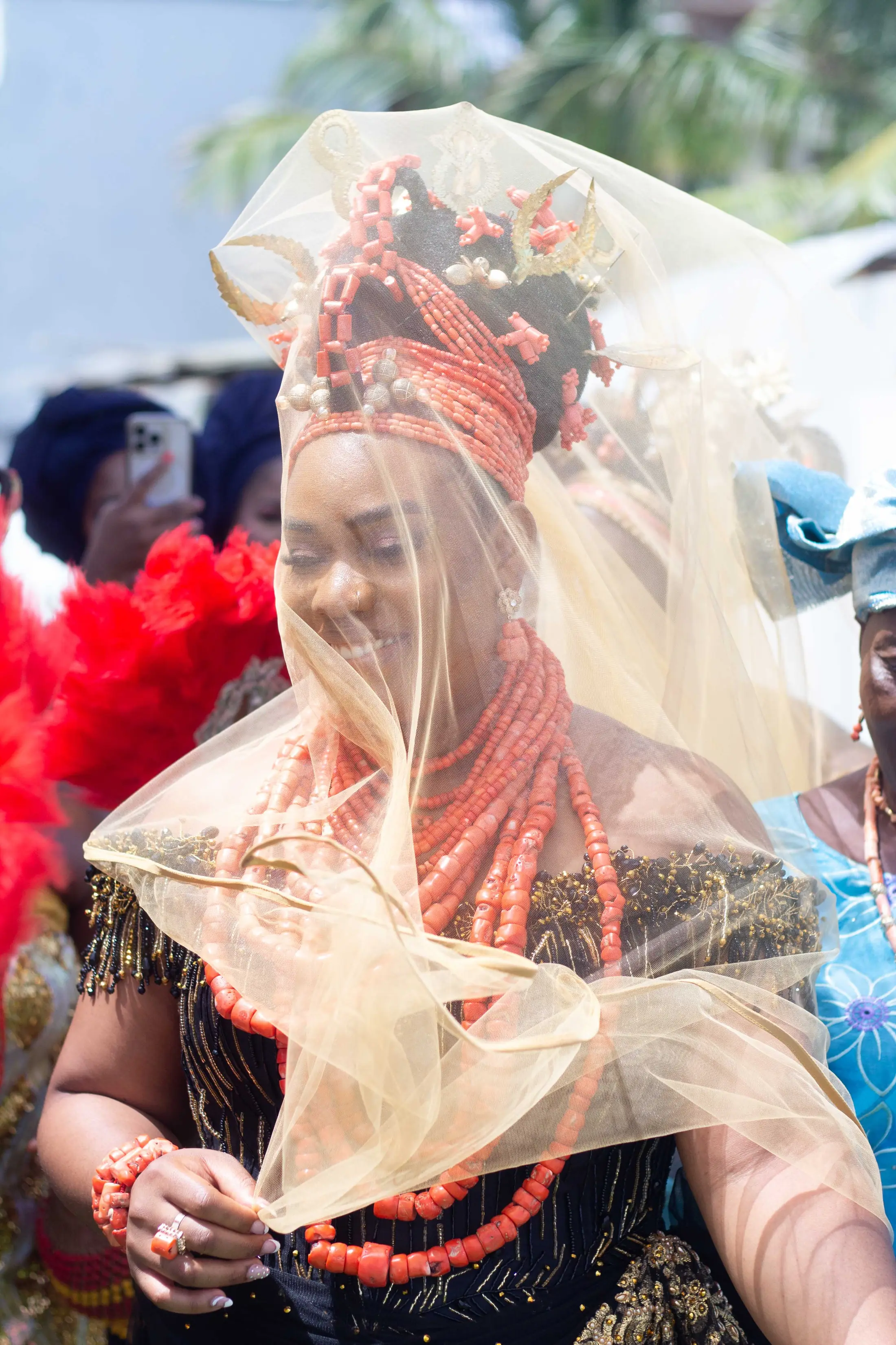 A bride in coral beads and a gold veil at her traditional wedding