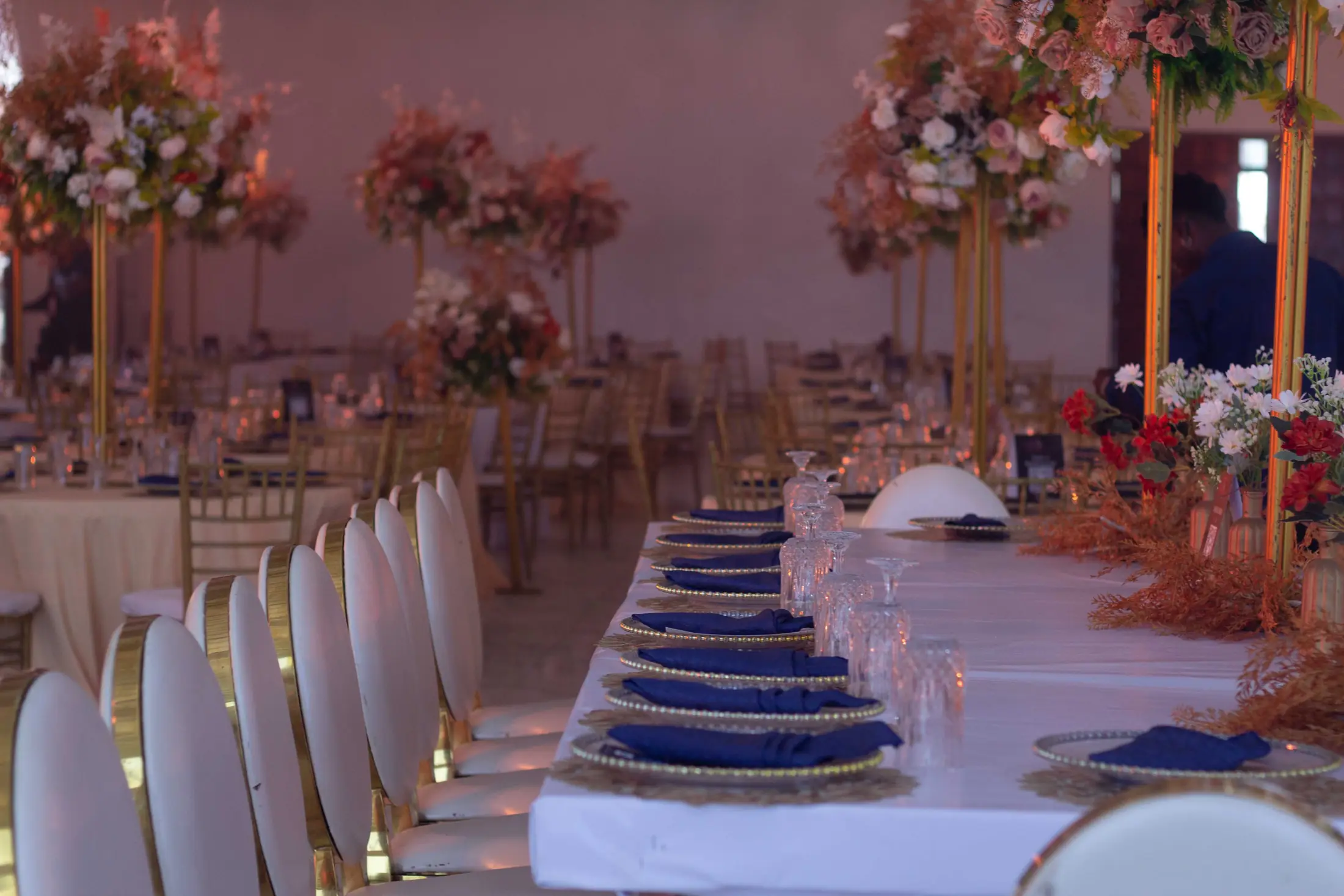 A long reception table set with blush flowers and gold cutlery